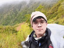 a man wearing glasses and a hat is standing in a field