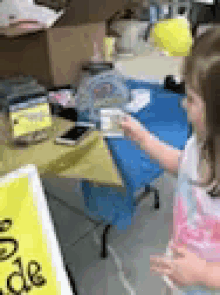 a little girl is standing in front of a table with a sign that says ' order ' on it .