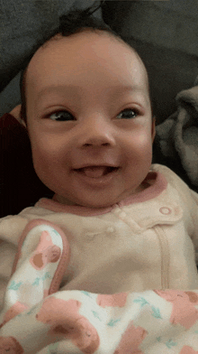 a baby is smiling and wearing a pink and white outfit