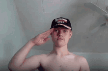 a shirtless man wearing a trump hat salutes