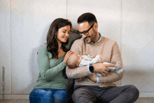 a man and woman are sitting on the floor with a baby