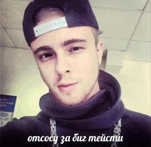 a young man wearing a hat and a hoodie with the words omcocy za duz meicmu below him