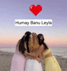 three girls hugging on a beach with a pixel heart above them that says humay banu leyla