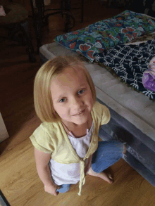 a little girl is sitting on the floor in front of a mattress