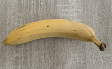 a banana is sitting on a wooden surface with a black spot on it