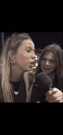 two women are talking into microphones and one of them is holding a microphone .