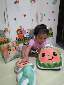 a little girl is playing with a stuffed watermelon