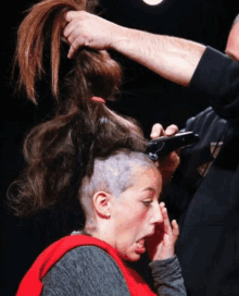 a woman is getting her hair cut by a man with a shaved head