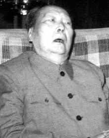 a black and white photo of a man sitting in a chair .