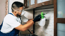 a man wearing a mask and gloves is spraying a wall with a spray bottle