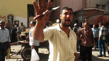 a man holds up a knife in front of a sign that says ' a ' on it