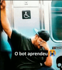 a man covering his face on a subway train with the words o bot aprendeu below him