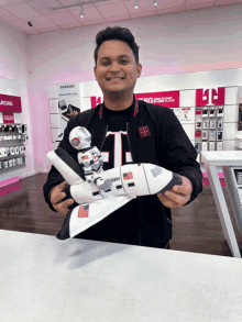 a man in a black t-mobile jacket is holding a toy rocket