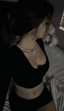 a woman wearing a black crop top and pearl necklace