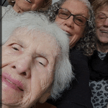 a group of older women are posing for a picture and one of them is wearing glasses