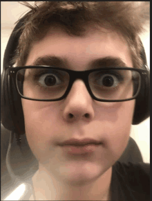 a young boy wearing glasses and headphones makes a face