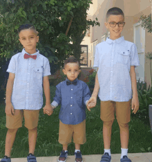 three young boys wearing bow ties and shirts holding hands