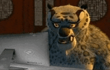 a cartoon leopard is sitting at a desk in front of a laptop computer .