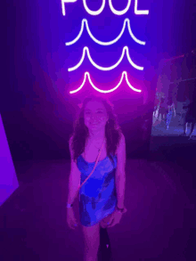 a girl stands in front of a neon sign that says pool