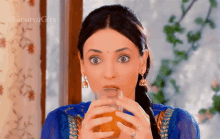 a woman drinking a glass of orange juice with sanaya gies written on the bottom