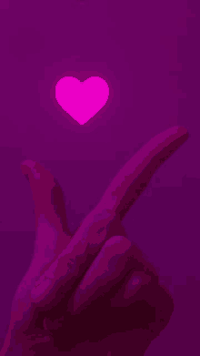 a hand is pointing at a pink heart floating in the air