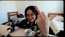 a woman wearing headphones sits at a table with a cup of coffee in front of her