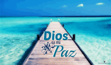 dios es mi paz is written on a wooden pier overlooking the ocean