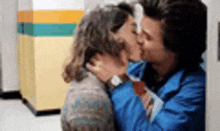 two people are kissing in a hallway .