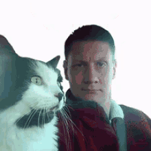 a man is holding a black and white cat in front of his face