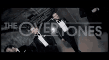 a group of men in tuxedos and bow ties are standing in front of the words the overtones