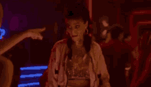 a woman in a pink jacket is dancing in a dark room with a crowd of people .