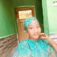 a woman wearing a turban is standing in front of a green door