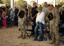 a group of people in military uniforms are standing in front of folding chairs with a a on them