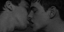 a couple of men are kissing each other in a black and white photo .