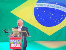 a man stands at a podium with vamos juntos brasil written on it