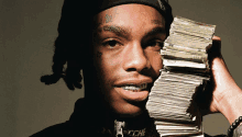 a man holding a stack of money in front of his face