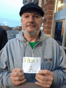 a man holds up a sign that says xbox 1