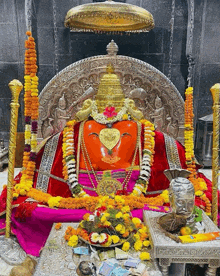 a statue of a deity is surrounded by flowers and garlands in a temple