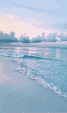 a beach with waves crashing against the shore at sunset