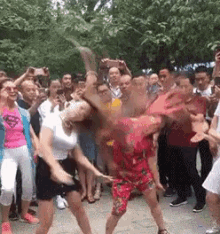 two women are dancing in front of a crowd of people . one woman is wearing a superman shirt .