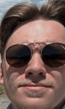 a close up of a man wearing sunglasses and a mustache .