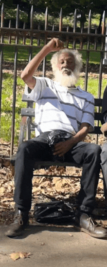 a man with a beard is sitting on a bench in a park