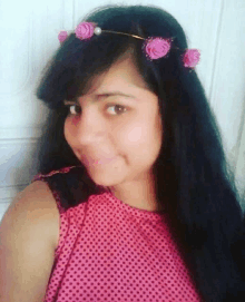 a girl wearing a pink polka dot top and a flower crown on her head