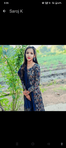 a woman in a blue dress is standing in front of a tree with the name saroj k on the bottom