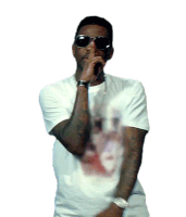 a man wearing sunglasses and a white t-shirt has his finger to his mouth