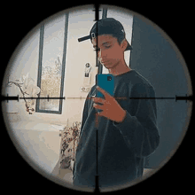 a young man is taking a selfie in a bathroom with a sniper scope in the background .