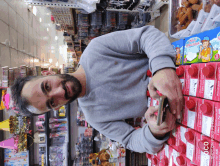 a man holding a cell phone in front of a display of milk