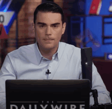 a man sitting in front of a laptop with the daily wire written on it