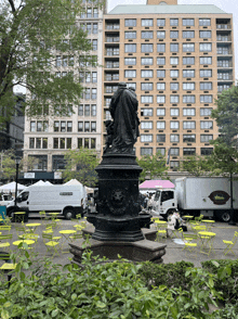 a statue in a park with a building in the background that says ' abercrombie & fitch ' on the front