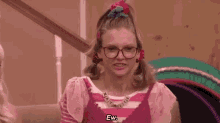 a woman wearing glasses and pigtails is sitting on a couch and making a funny face .